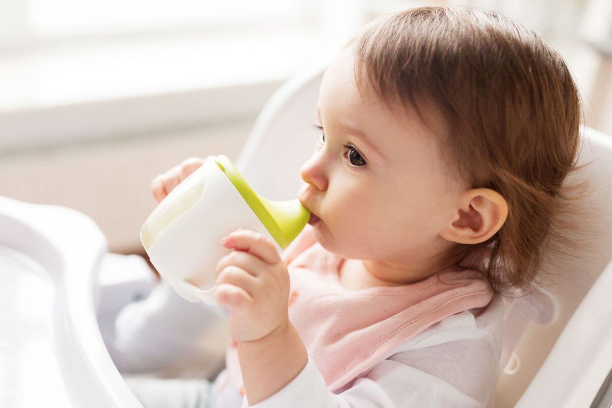 Bebê segurando um copinho de aprendizagem
