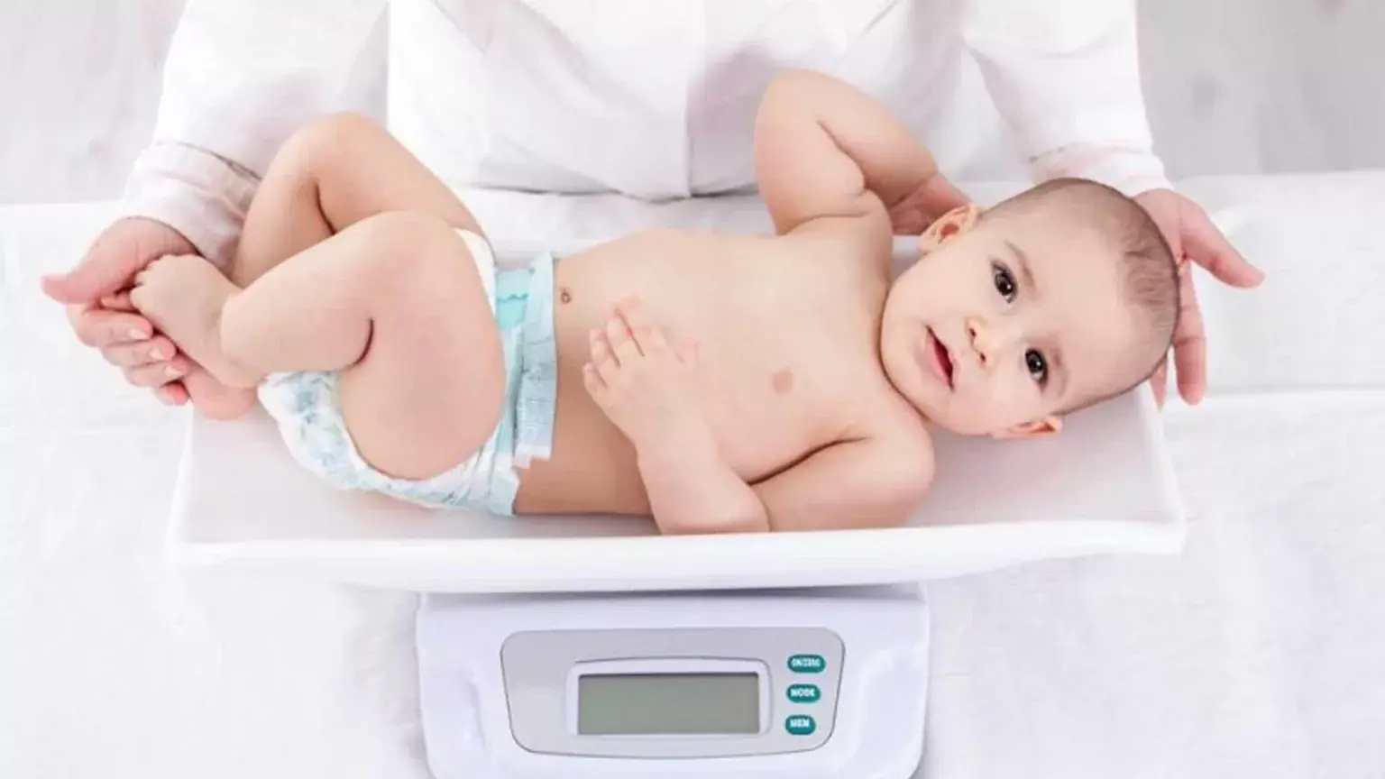 Bebê deitado sendo pesado em uma balança pediátrica