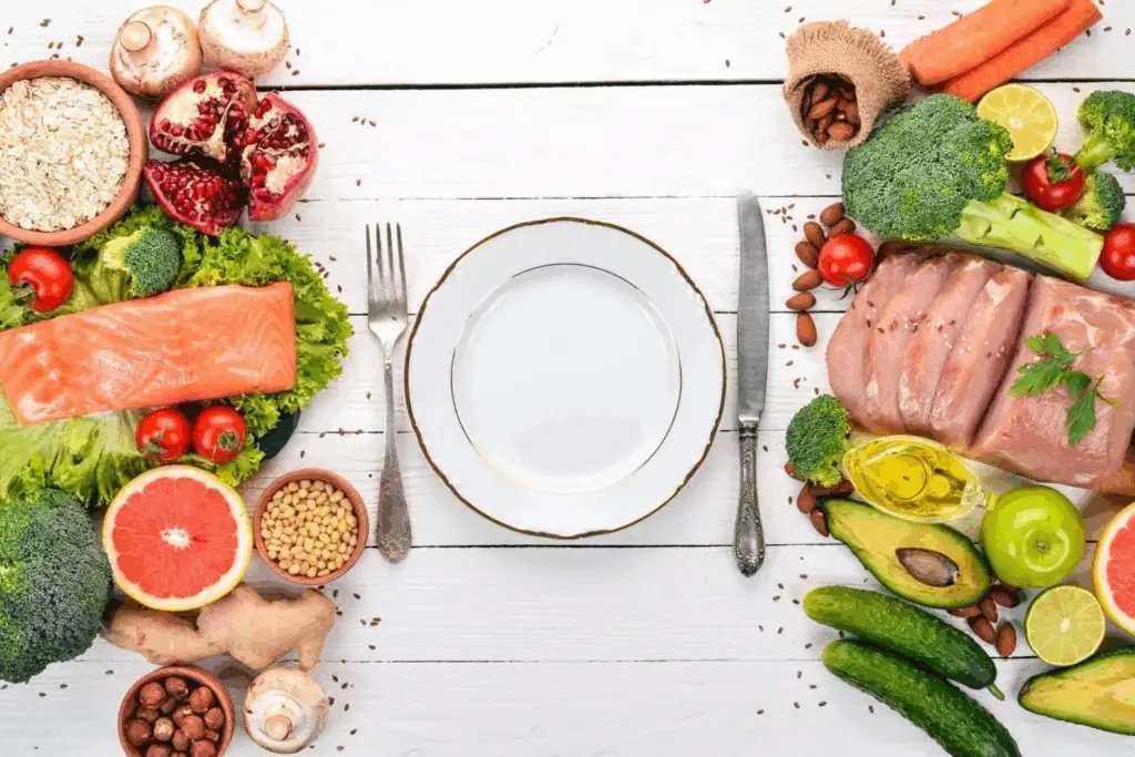 Prato vazio cercado de salmão, carnes, frutas, legumes e grãos