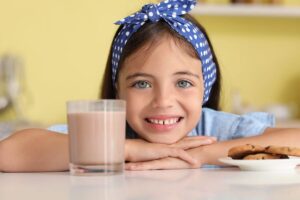 menina sorrindo com copo de achocolatado
