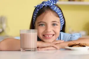 menina sorrindo com copo de achocolatado