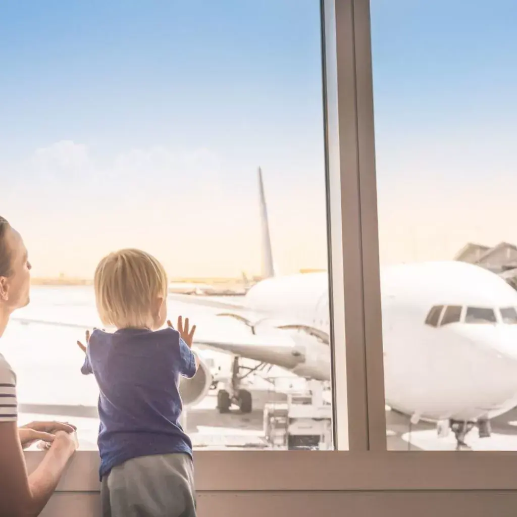 Criança olhando um avião pela janela do aeroporto