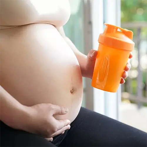 Gestante segurando garrafa de Whey Protein
