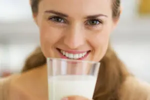 Mulher feliz tomando leite para aumentar as chances durante a FIV