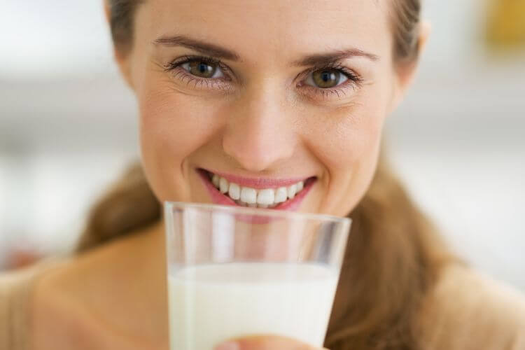 Mulher feliz tomando leite para aumentar as chances durante a FIV