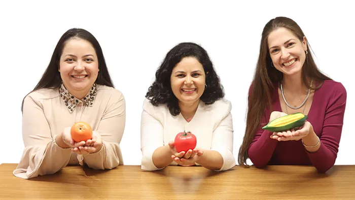 Nutricionistas materno-infantis da Clínica Paula Stancari segurando alimentos saudáveis