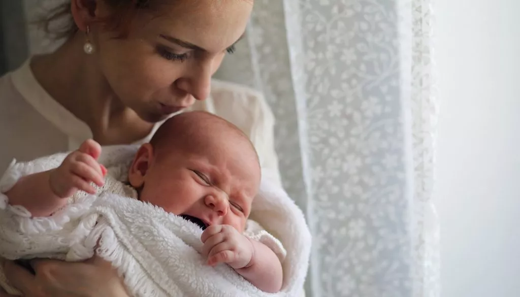 Lactante segurando seu bebê com cólica 